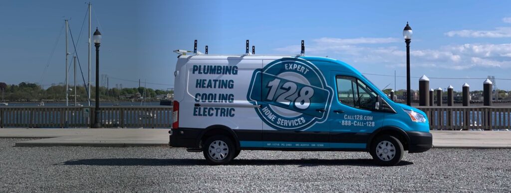 A blue and white van parked by a waterfront promotes plumbing, heating, cooling, and electric services with the number 128.