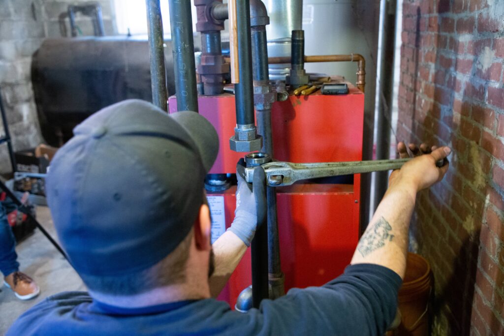 128 Plumbing technician working on boiler in basement 