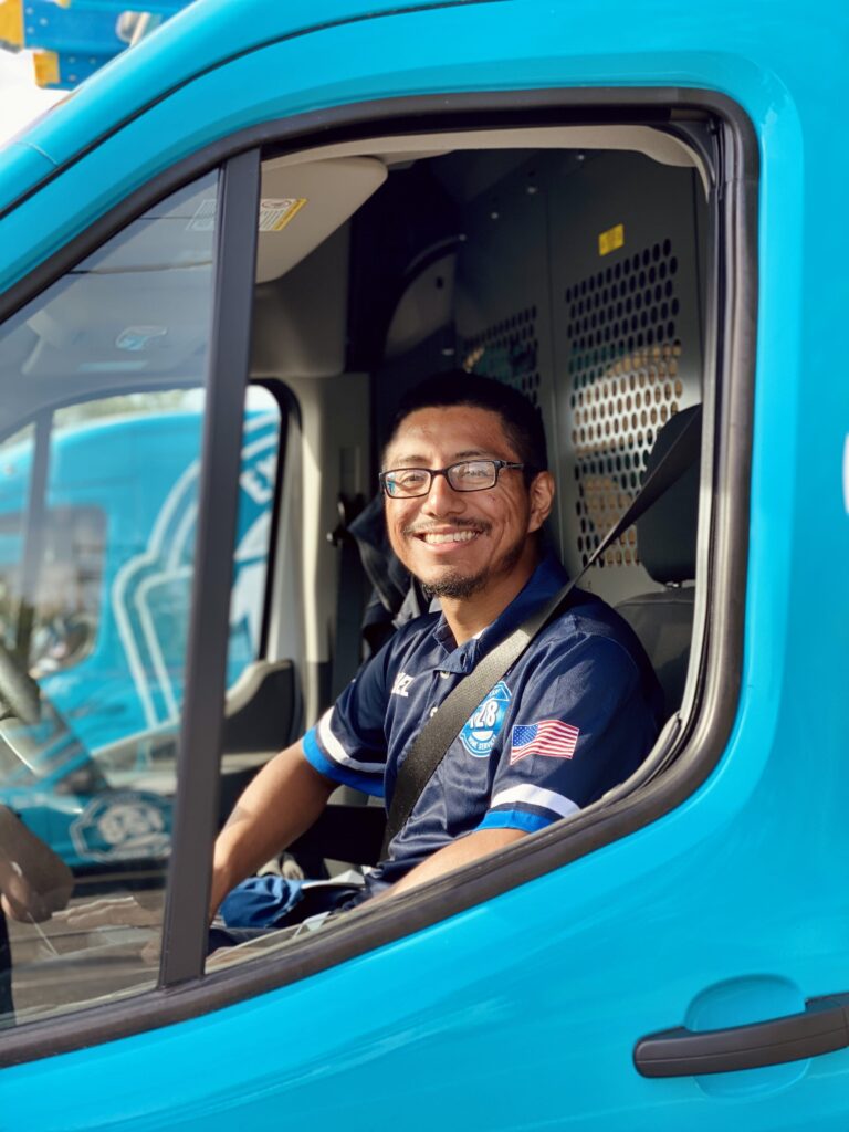 128 technician in drivers seat of 127 van smiling 