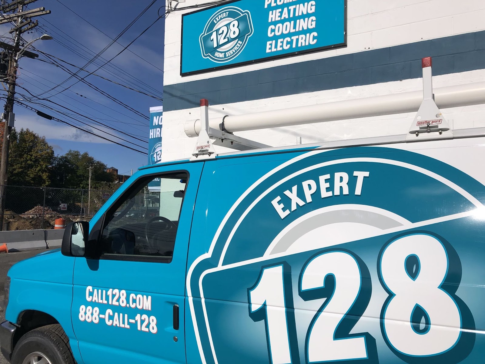 A white van with "Expert 128" and company details parked near a building with the same branding.