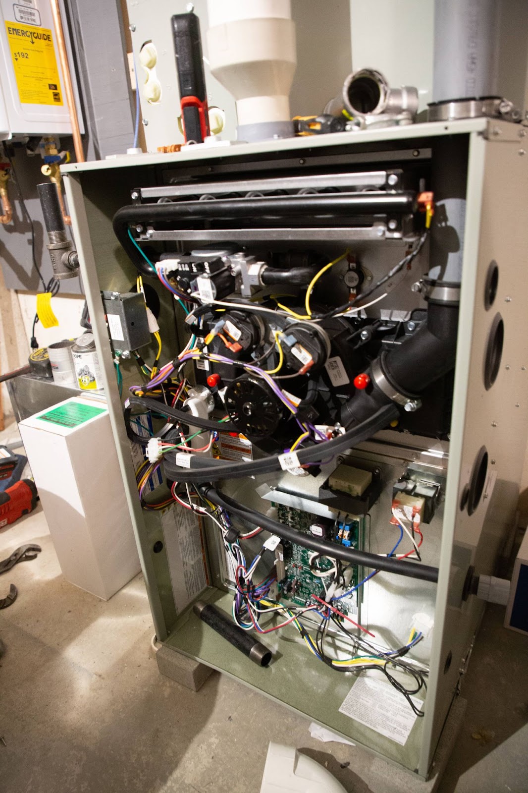 Open furnace showing internal components and wiring in a basement.