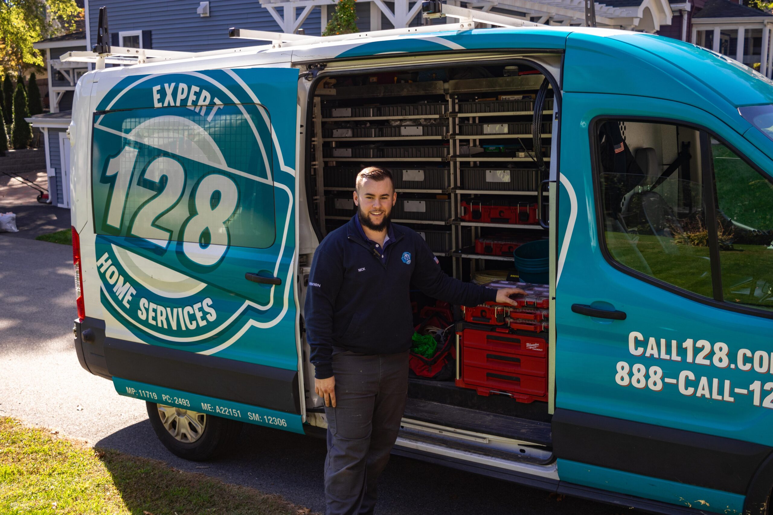 A 128 Plumbing electrician smiling in front of 128 Plumbing truck after doing electrician services in Winchester, MA.