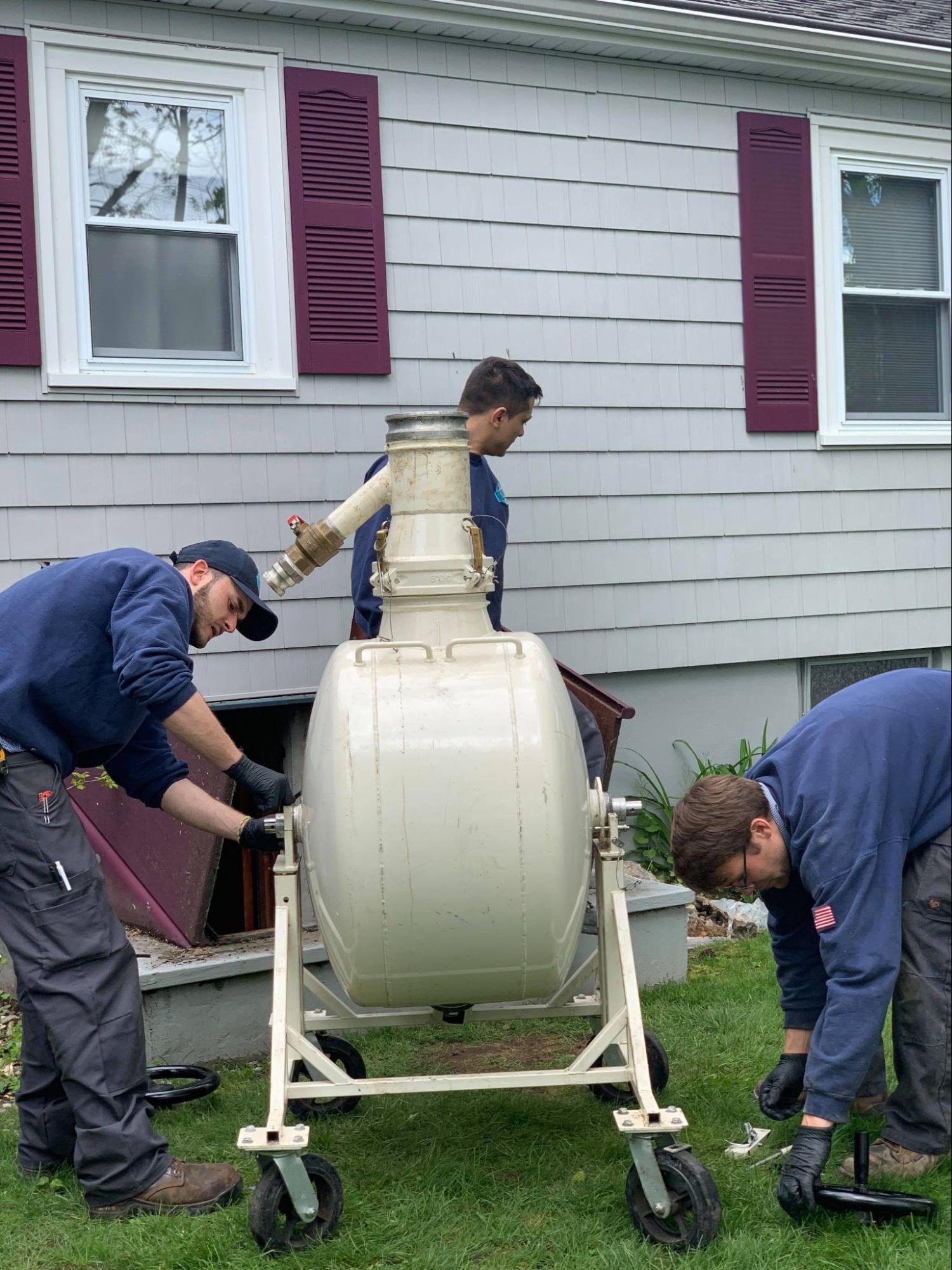 Three people doing a drain cleaning service in newton MA from 128 Plumbing.