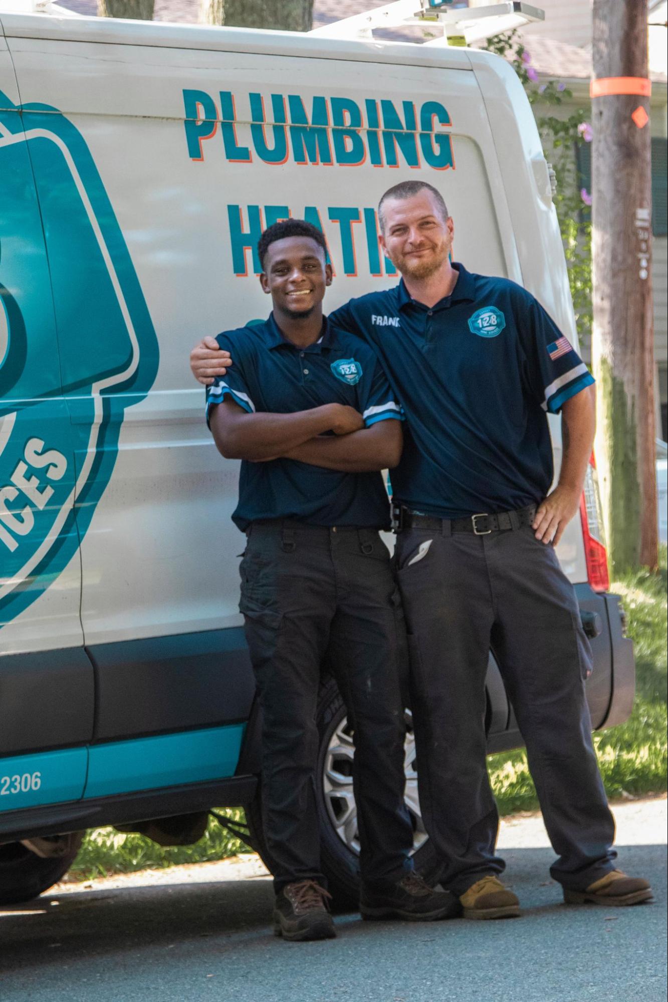 Two 128 Plumbing employees smiling in front of truck for an HVAC company in Littleton MA