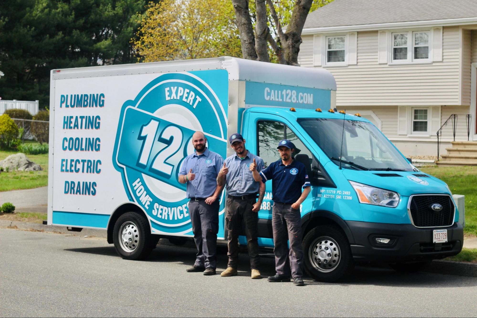 Three workers for 128 Plumbing an air conditioning company in Lexington MA smiling in front of truck.