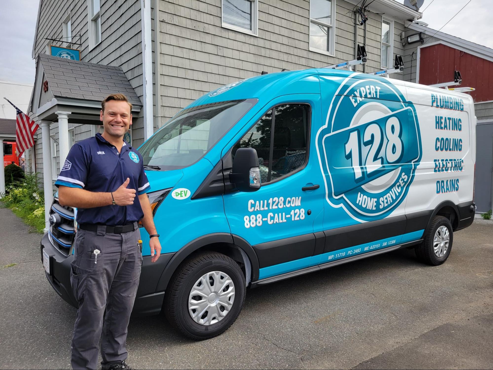 Man in uniform giving a thumbs-up stands next to a blue and white "128 Expert Home Services" van parked in front of a building.