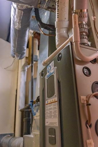 Residential HVAC system showing ducts, pipes, and a furnace unit installed in a utility room.